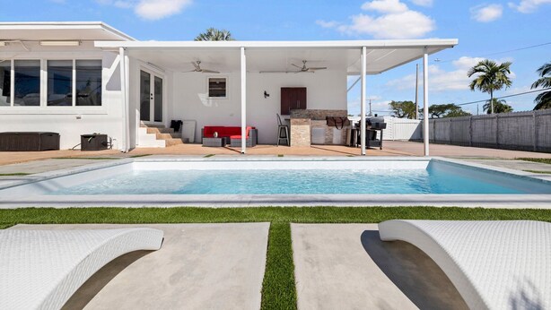 Uma casa moderna com piscina, varanda coberta e área para churrasco.
