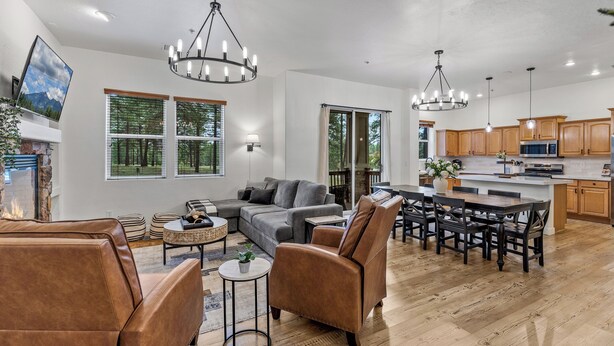 A spacious living area with a fireplace, a large gray sectional sofa, a brown leather armchair, and a dining table with chairs.