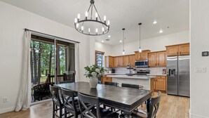 A modern kitchen with wooden cabinets, a stainless steel refrigerator, and a dining area with a large table and chairs.