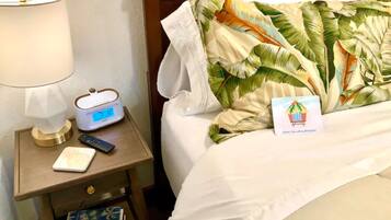 Ein Hotelzimmer mit einem Bett, einem Nachttisch mit Lampe, einer digitalen Uhr und einer Fernbedienung.