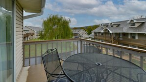 A balcony with a round metal table and chairs, overlooking a residential area with houses and a tree. - Memory Maker Condo - Great Location - Updated - Walk to Restaurant and Store! (Branson)