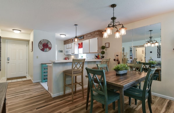Une cuisine moderne avec un plancher en bois, un îlot central et des luminaires suspendus.