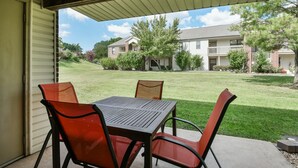 A covered patio with a table and chairs, overlooking a well-maintained lawn and a row of houses. - Southern Paradise - Resort Amenities - Close to Downtown and the Branson Landing (Branson)