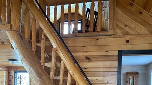 Una escalera de madera en un interior tipo cabaña con un altillo.