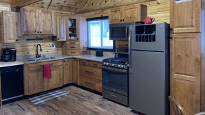 Una cocina con armarios de madera, un refrigerador de acero inoxidable, una estufa y un microondas.
