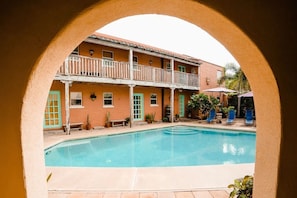 Une cour avec une piscine, un bâtiment doté d’un balcon et des sièges à l’extérieur.