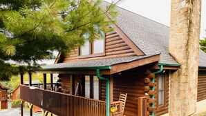 Eine Blockhütte mit Veranda, einer Holzterrasse und einem Steinkamin.