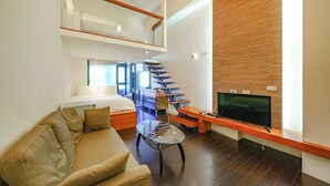 A modern hotel room with a glass coffee table, a sofa, a TV on a wooden stand, a staircase, and a bed with a nightstand. - Le Lu (Jiaoxi)