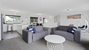 Un salon moderne avec des canapés gris, une table basse blanche et un fauteuil suspendu.