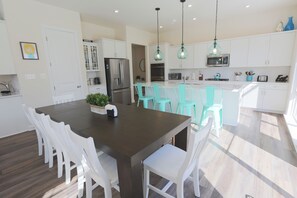 A modern kitchen with white cabinets, a stainless steel refrigerator, and a central island with turquoise chairs. - The Perfect Summer Vacation Home for Family & Friends - Minutes to Bethany Beach (Ocean View)