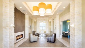 Amplia sala de estar con chimenea, sillones de cuero, una mesa de centro de vidrio y un comedor con sillas y una mesa.