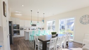 Una cocina moderna con armarios blancos, una isla central con sillas y una mesa de comedor.