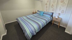 Un dormitorio con cama, mesita de noche, lámpara y decoración en la pared.