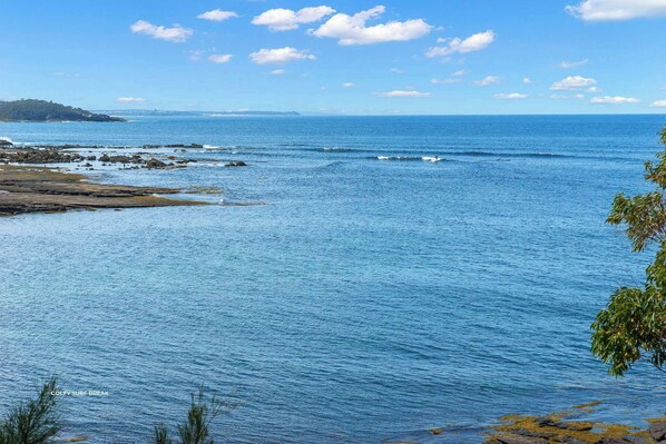 A coastal landscape with calm sea, rocky shore, and distant landmass. - Fairwater In Mollymook (Mollymook)