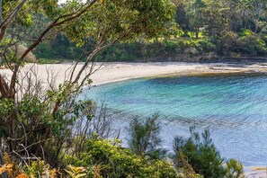 A beach with clear water, surrounded by greenery and trees. - Fairwater In Mollymook (Mollymook)
