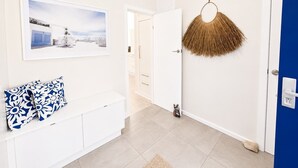 Un pasillo con una mesa consola blanca, un cuadro en la pared y una puerta azul.