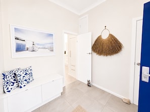 A hallway with a white console table, a framed picture on the wall, and a blue door.