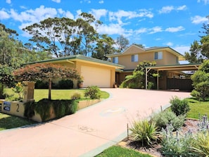 A two-story house with a garage, a covered driveway, and a well-maintained lawn.