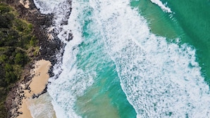 An aerial view of a beach with waves, rocky areas, and greenery. - Sticks By The Sea at Manyana (Manyana)