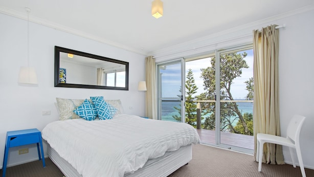 A hotel room with a bed, a chair, a balcony with a view, and a large mirror. - Sticks By The Sea at Manyana (Manyana)
