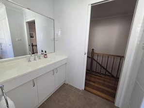 A bathroom with a white sink, mirror, and cabinets.