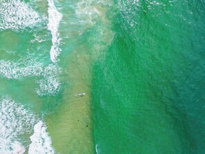 An aerial view of a coastal area with clear water and waves.
