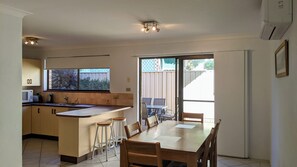Enjoy casual dining in this kitchen and dining area with a central island, sink, and microwave, surrounded by a view of lush greenery.