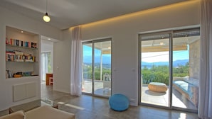 Ein modernes Wohnzimmer mit einem großen Schiebeglasfenster, das auf einen Balkon mit Bergblick führt.