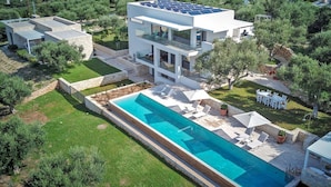 Ein modernes, zweistöckiges Haus mit Schwimmbad, Solaranlage und Garten.