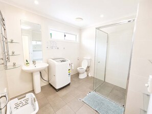 A modern bathroom with a glass shower enclosure, a white sink, and a toilet.