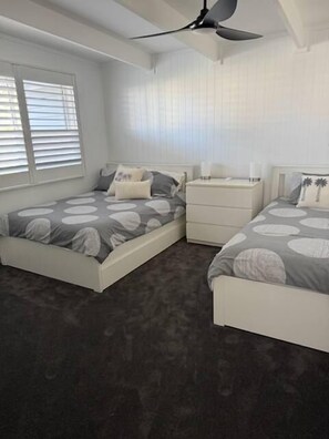 Un dormitorio con dos camas, una mesita de noche y un ventilador de techo.
