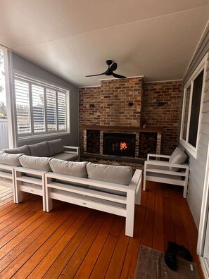 Un espacio de sala acogedor con chimenea, ventilador de techo y disposición de asientos.