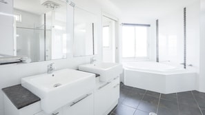 A modern bathroom with two sinks, a bathtub, and a shower.