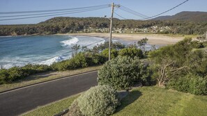 A coastal road with a beach and houses in the background.