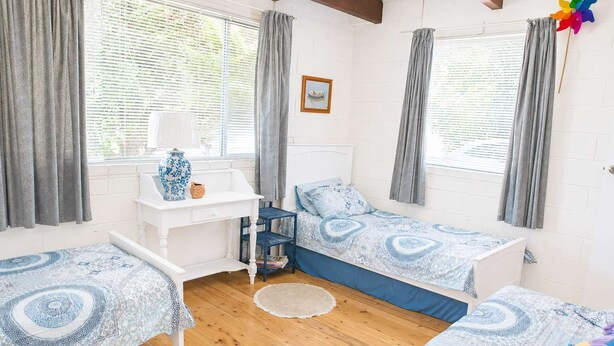 Une chambre avec deux lits simples, un bureau et une chaise.