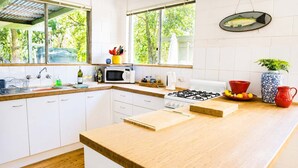 Une cuisine moderne avec des meubles blancs, un plan de travail en bois, une cuisinière à gaz, un four à micro-ondes et un évier.