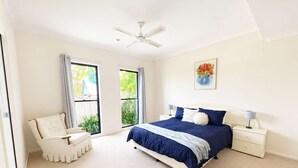A bedroom with a bed, nightstands, a chair, and a ceiling fan.