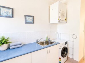 Una cucina moderna con lavello, lavatrice e una pianta in vaso.