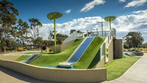 A playground with two slides, artificial grass, and a concrete pathway. - Jillbys House at Narrawallee (Narrawallee)