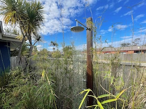 Un jardín con fuente de agua, pastos altos y valla de madera.