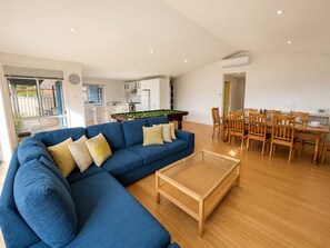 Un salon moderne avec un canapé bleu, une table basse en bois et un coin repas comprenant des chaises et une table en bois.