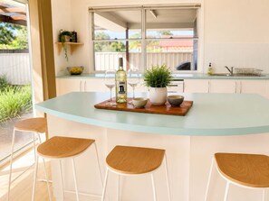 Un îlot de cuisine avec un plateau en verre, une bouteille de vin et trois bols.