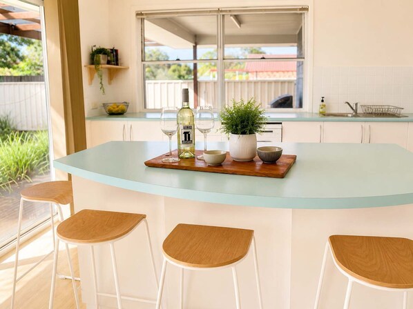 A kitchen island with a glass top, a bottle of wine, and three bowls.