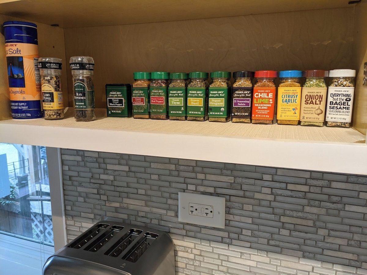 A kitchen shelf with various spice jars and a toaster.