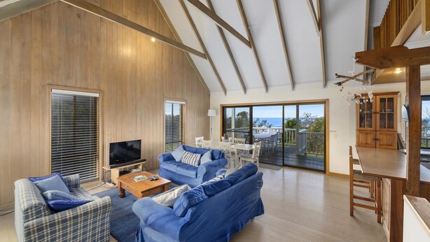 Amplia sala de estar con un sofá grande, un televisor y un comedor con vistas al exterior.