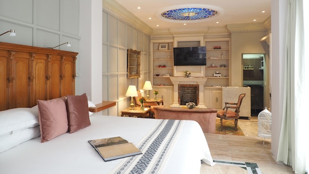 Une chambre d’hôtel avec un grand lit, une télévision, une cheminée et un coin repas.