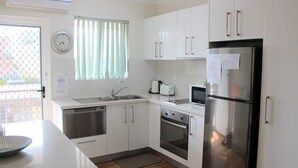 A modern kitchen with white cabinets, stainless steel appliances, a dishwasher, an oven, a microwave, and a refrigerator. - Sand & Sea 5 - Beach at your Doorstep (Sawtell)