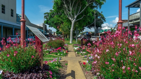 Un chemin bordé de parterres de fleurs aux couleurs vives, qui mène à un bâtiment sur lequel est apposée une enseigne.