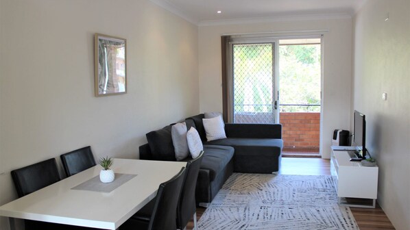 A modern living room with a dining table, a sofa, and a TV.