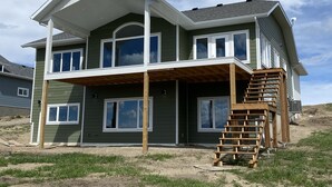 A two-story house with a covered porch and a wooden staircase leading to the upper level. - Brand new beautiful home with best view outside of Waterton Park. UPPER suite. (Mountain View)